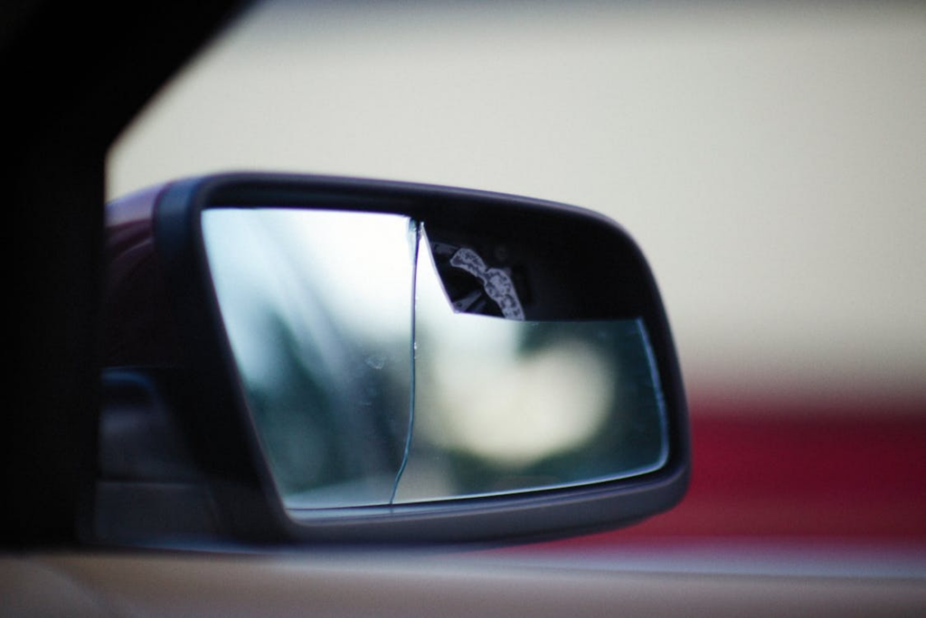  Close-up of damaged car side mirror showing broken glass requiring repair or replacement