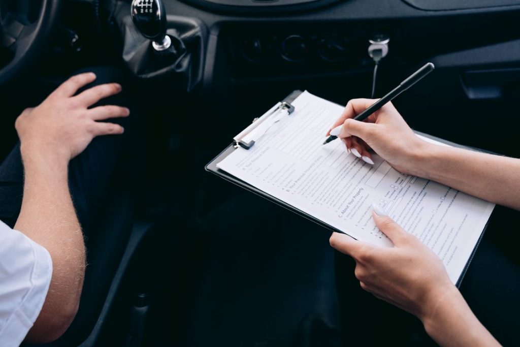 Person completing insurance paperwork inside vehicle during claim process