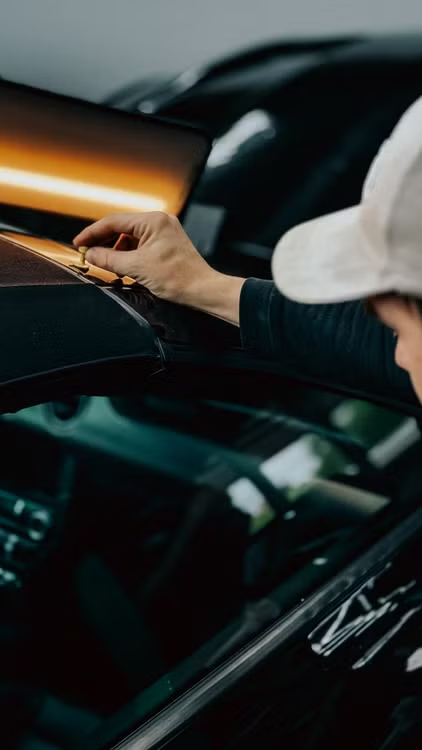 Technician using precision tool on windshield during repair work