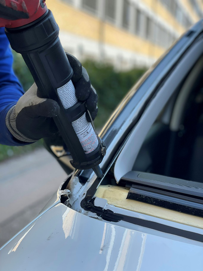 Auto glass technician preparing adhesive for windshield replacement installation