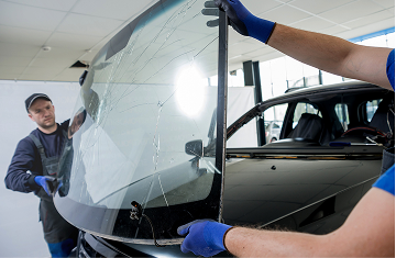 Technician replacing cracked windshield with a new one